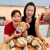 two women smiling holding sourdough bread