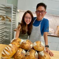two people smiling with sourdough breads