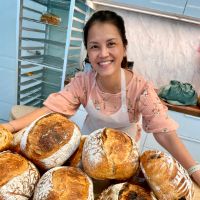 a woman smiling with a lot of sourdough breads