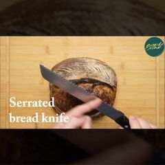 Person slicing a loaf of sourdough bread with a serrated knife on a wooden cutting board, sourdough tips tutorial