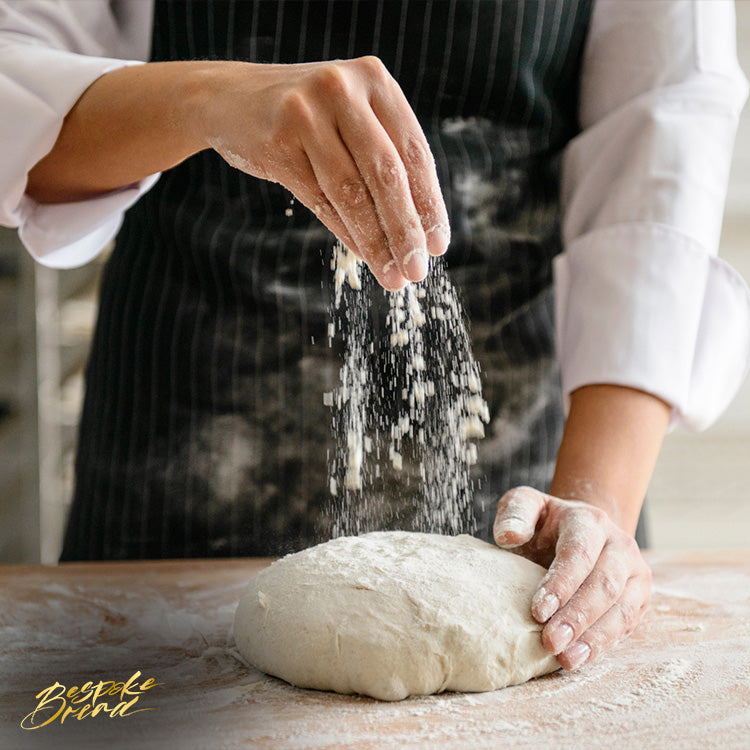 A baker dusting flour on a dough