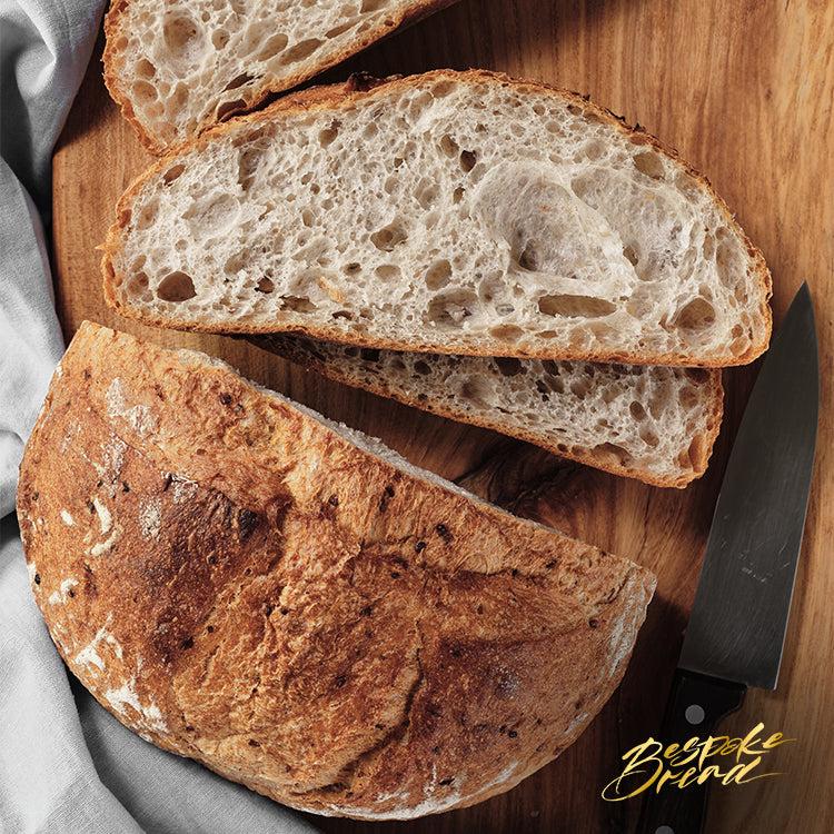 freshly baked sourdough bread loaf with crusty golden exterior and airy interior on wooden board